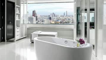 A modern bathroom with a freestanding bathtub, a bench, and a city view.