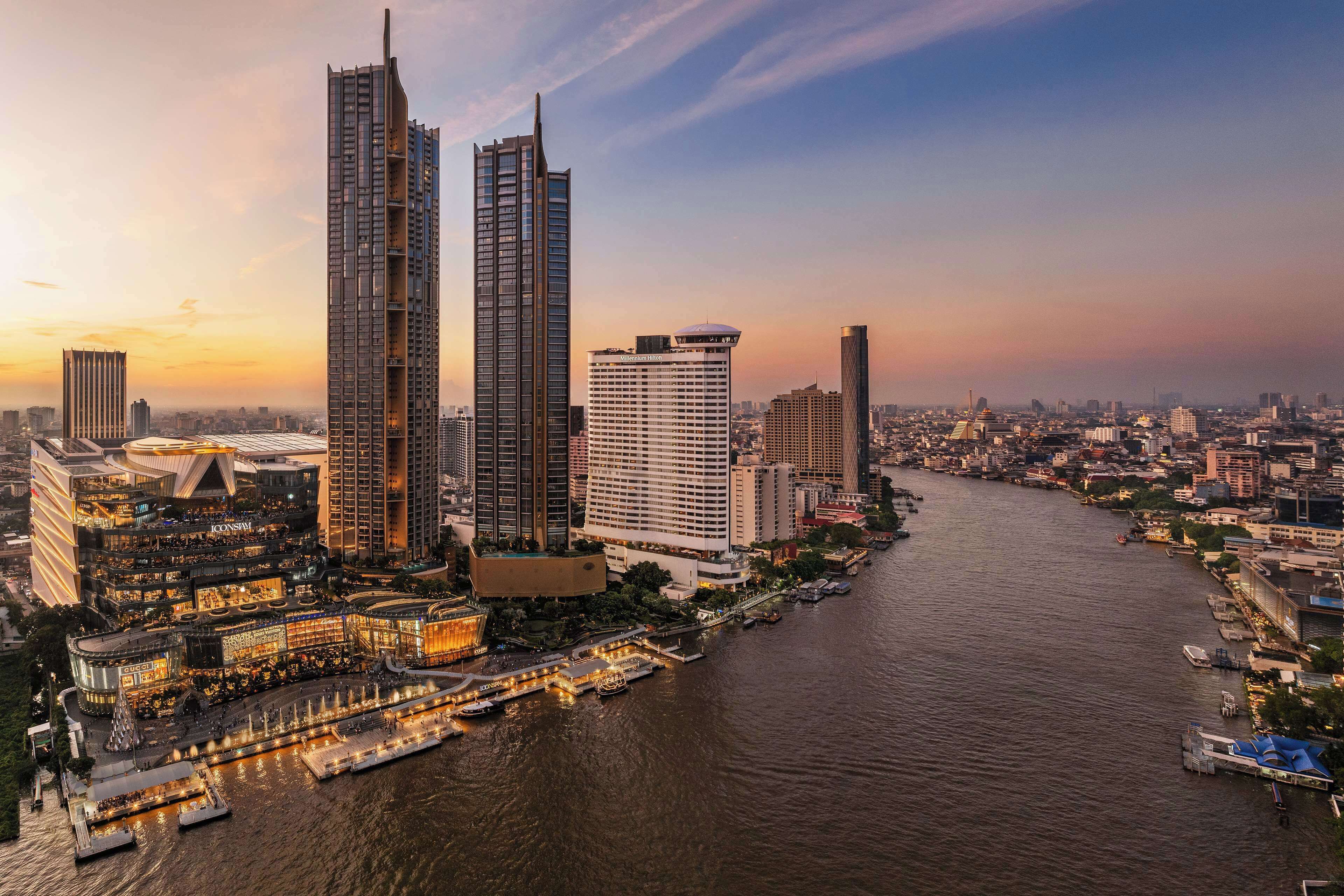 A cityscape with modern high-rise buildings, a river, and a waterfront promenade.