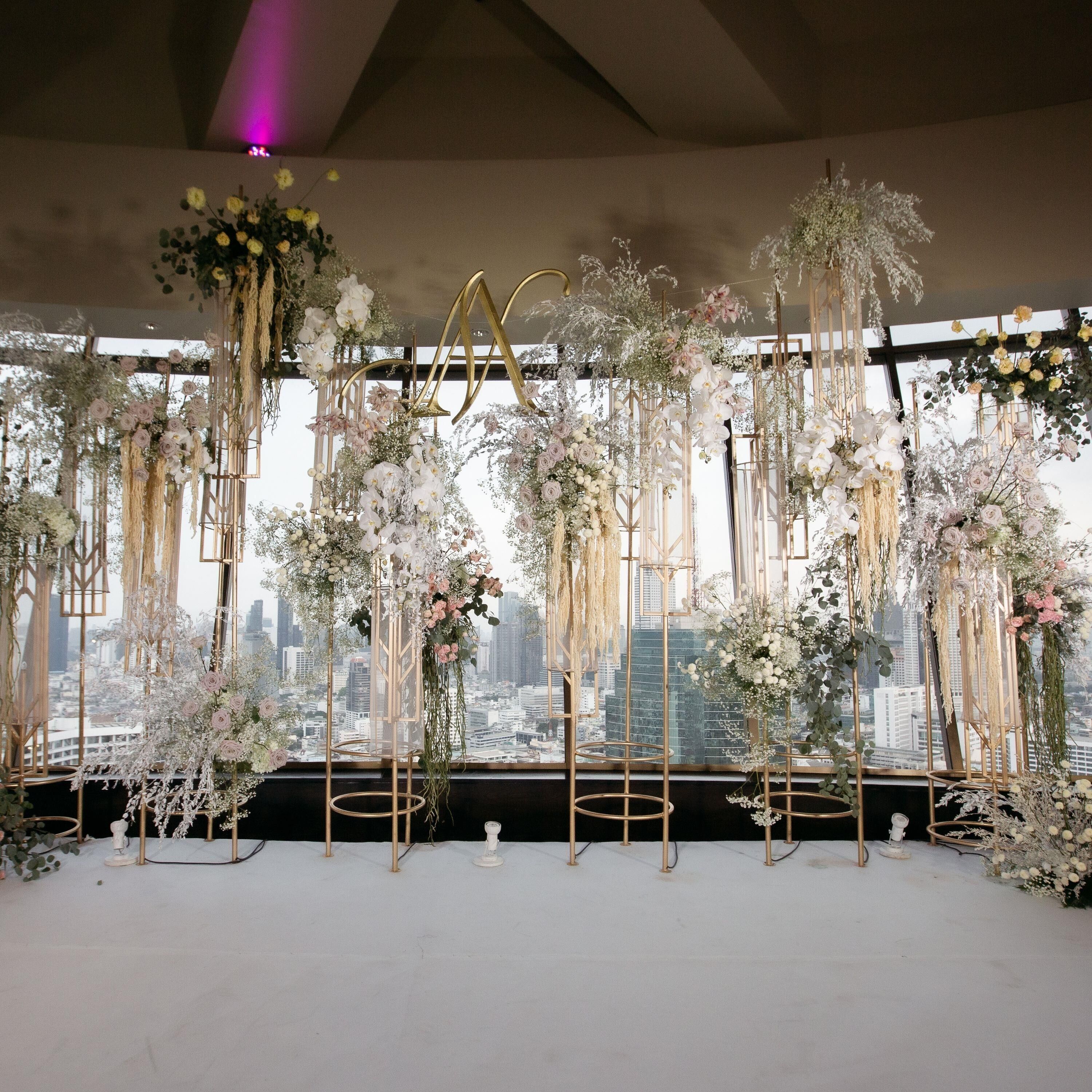 A room with a city view, decorated with floral arrangements and a large 'M' structure.