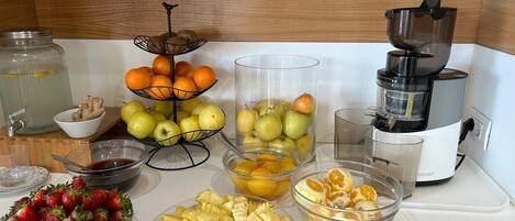 A kitchen counter with various fruits and a juicer.