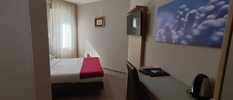 Une chambre d’hôtel avec un lit, un bureau, une chaise, une télévision et un tableau au mur.