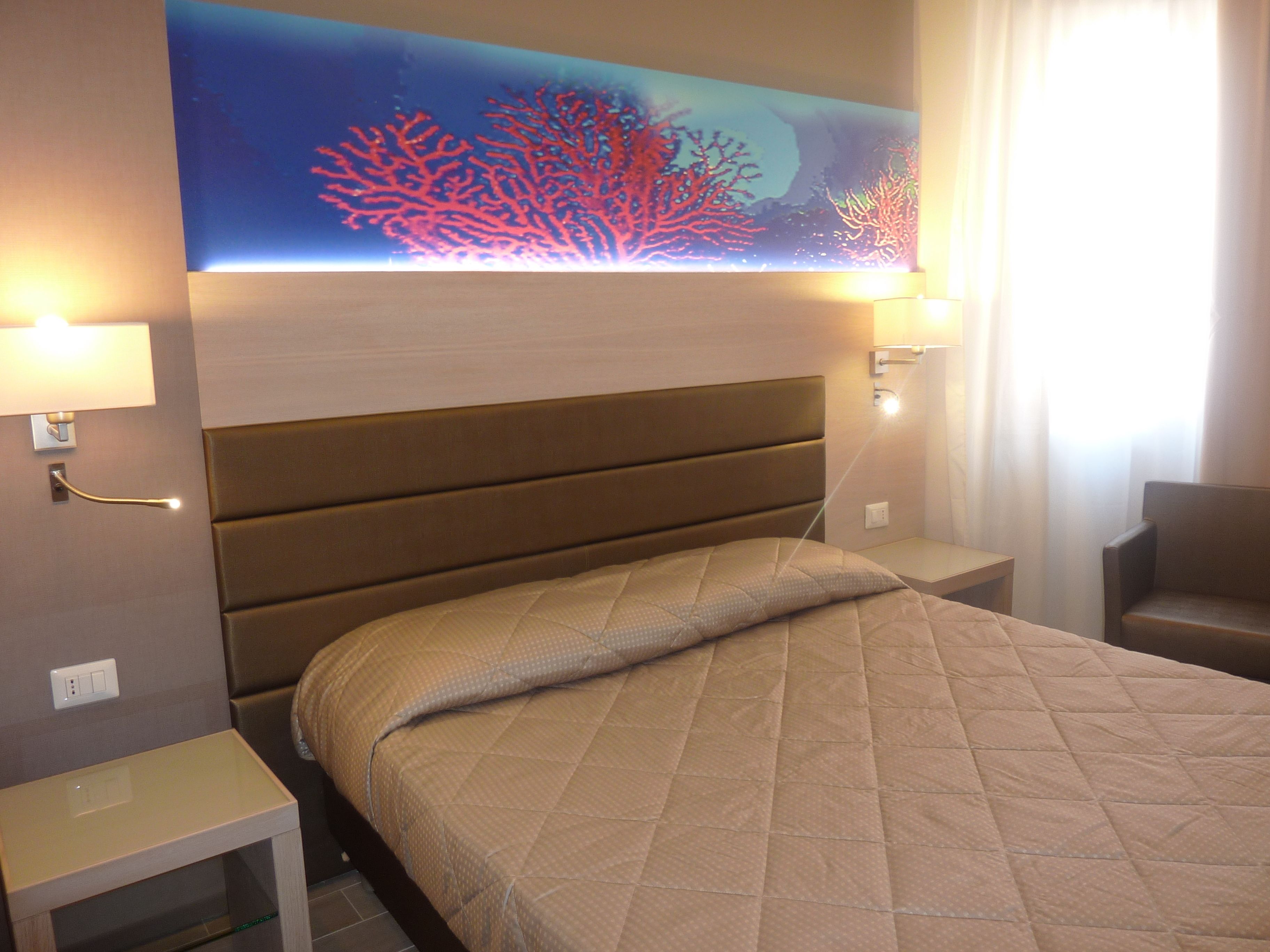 A hotel room with a bed, nightstands, and a wall-mounted artwork.