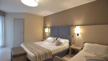 Une chambre d’hôtel avec un grand lit, des tables de chevet, une petite table et une lampe.