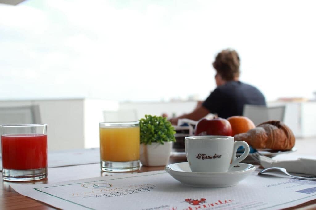 A breakfast setting with a croissant, orange, and a glass of orange juice on a table.