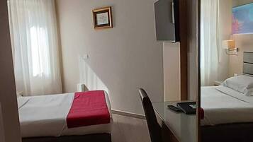 A hotel room with two beds, a desk, a chair, a TV, and a mirror.