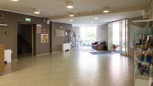 A spacious lobby with a reception desk, a staircase, and a glass display case with items. - Alma Di Alghero Hotel (Alghero)