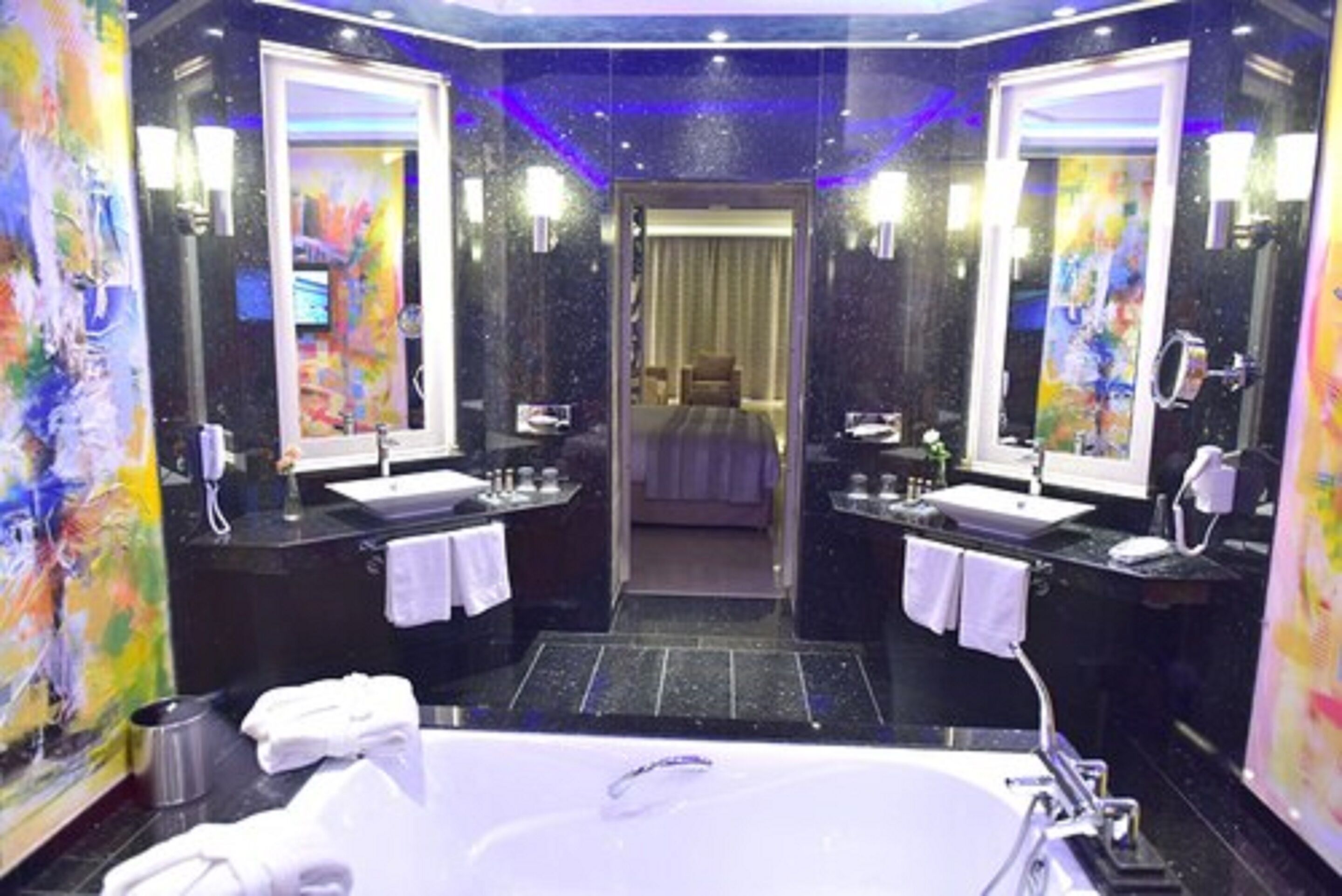 Une salle de bain moderne avec une grande baignoire, deux lavabos et un miroir.