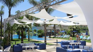 A poolside area with blue and white outdoor seating, a pool, and palm trees. - Zaki Hotel  (Meknes)