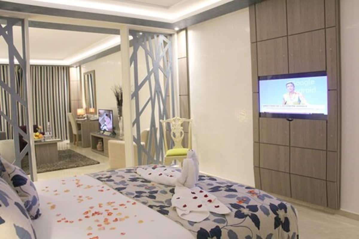 A hotel room with a bed, a TV screen, a desk, and a chair.