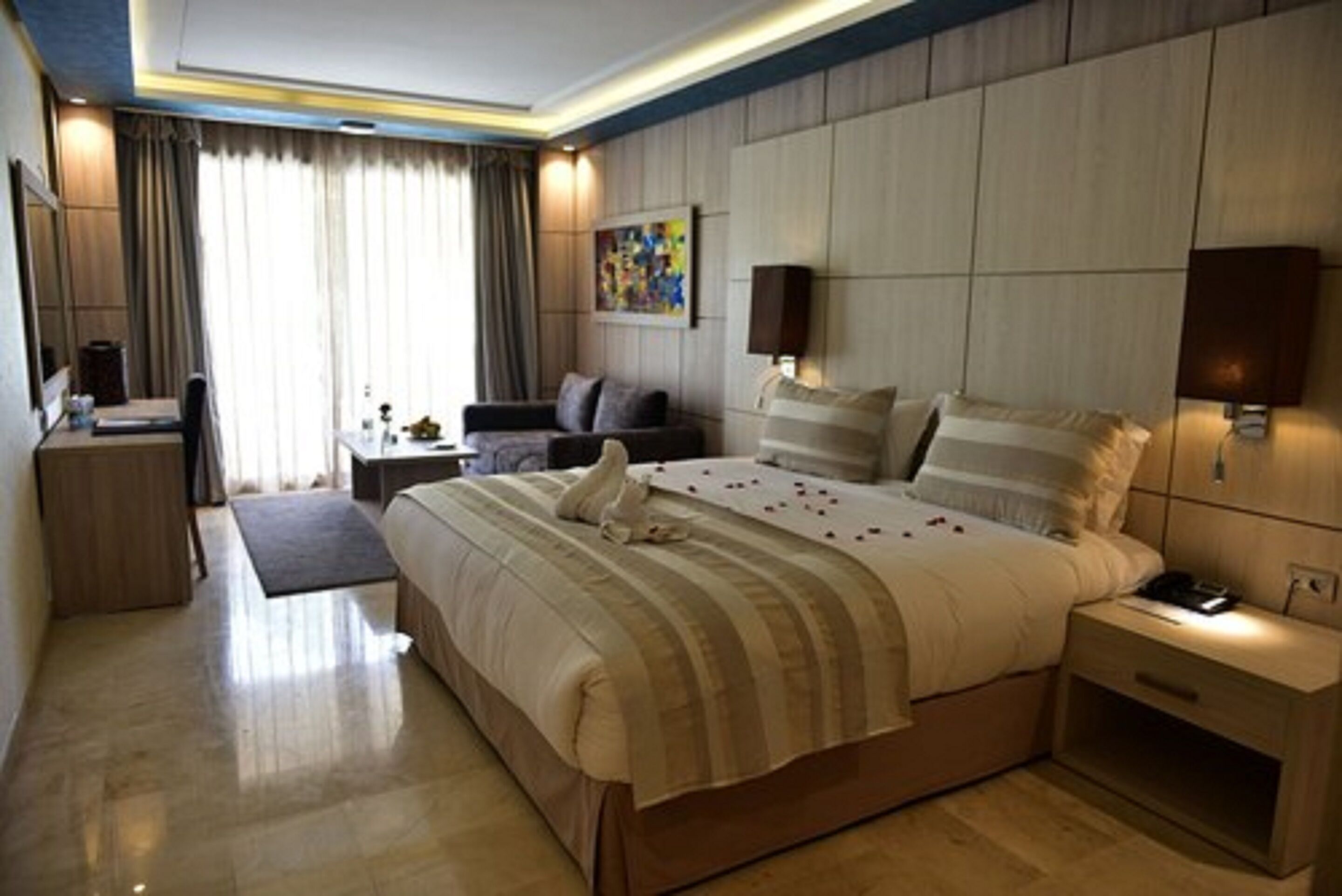 A modern hotel room with a large bed, bedside tables, a desk, and a chair.