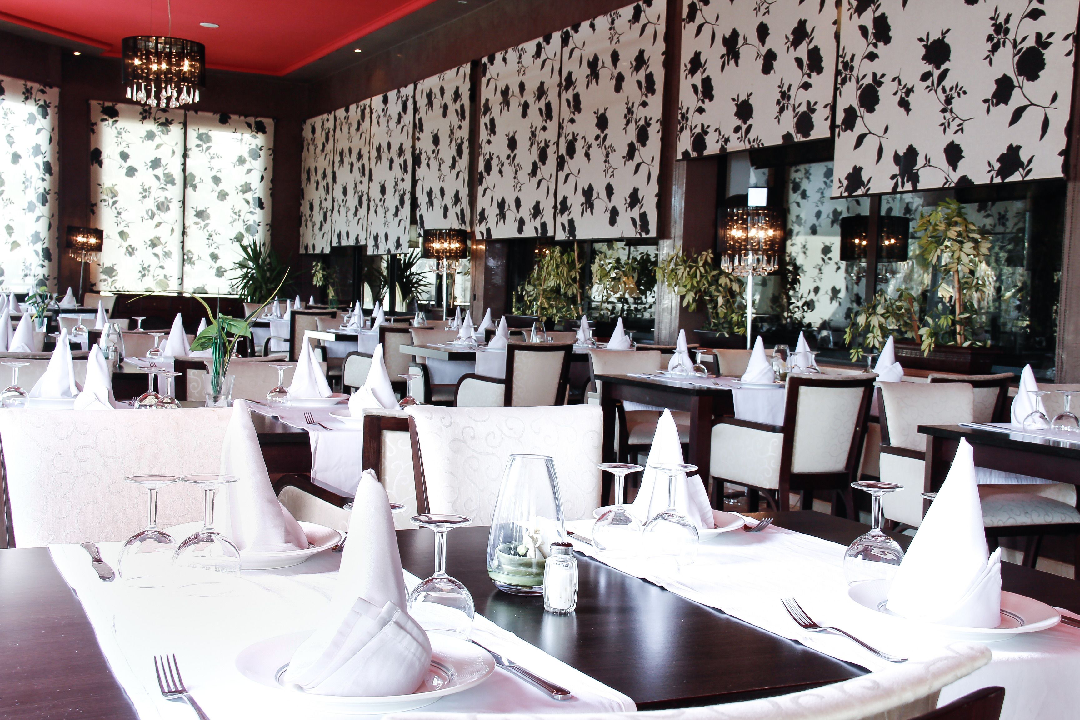 A restaurant with multiple tables set for dining, each with white napkins, cutlery, and wine glasses.