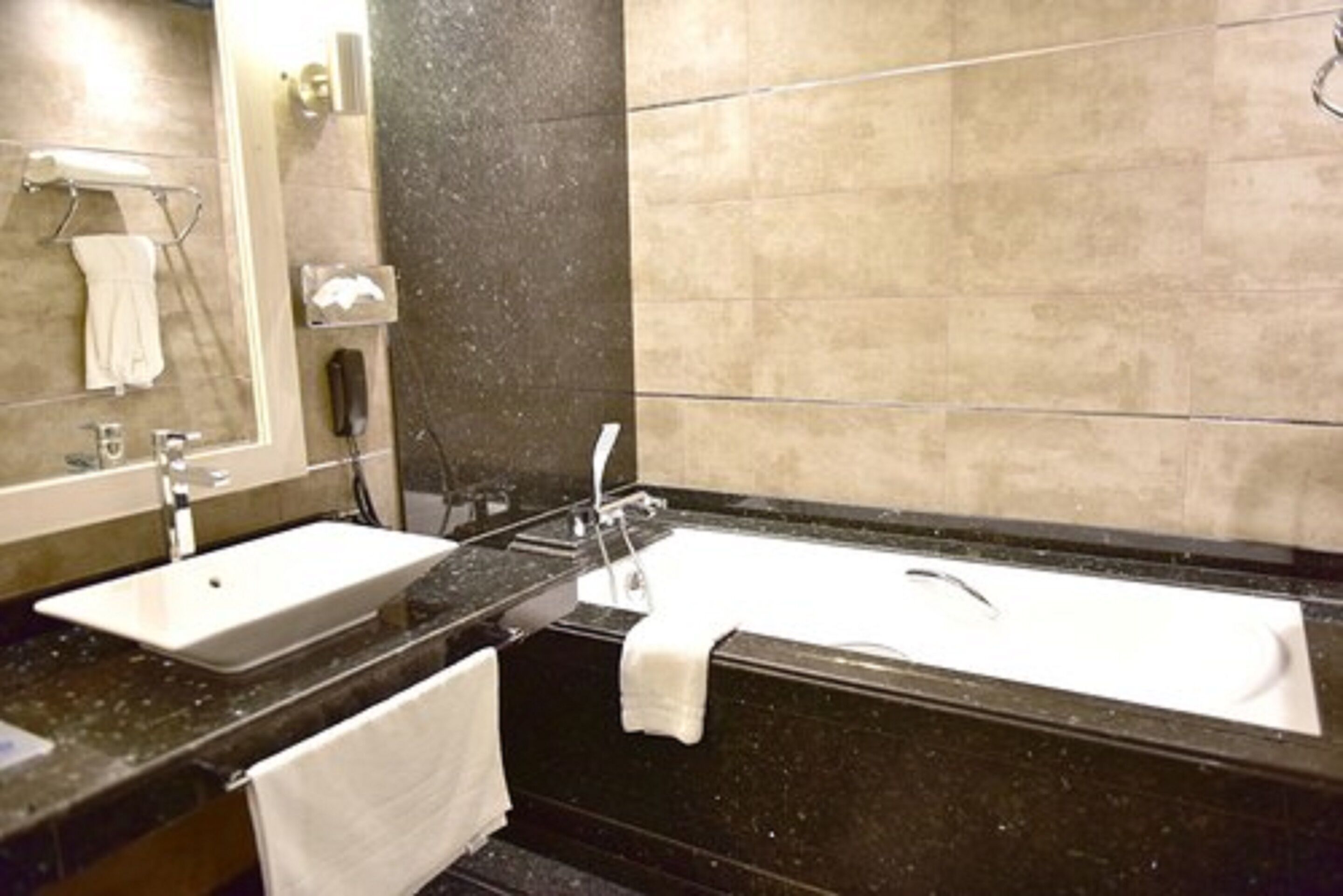 A modern bathroom with two sinks, a bathtub, and a mirror.