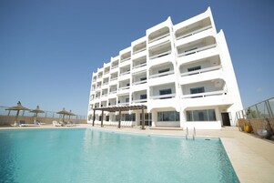 Una piscina al aire libre de temporada, sombrillas
