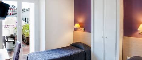 A hotel room with two beds, a desk, a chair, a TV, and a sliding door to a balcony.