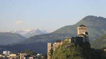 A historic castle on a hill overlooking a town with mountains in the background.
