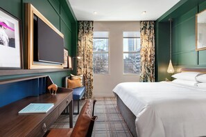 A hotel room with a bed, a desk with a chair, a television, and a window with curtains. - Glenn Hotel, Autograph Collection (Atlanta)