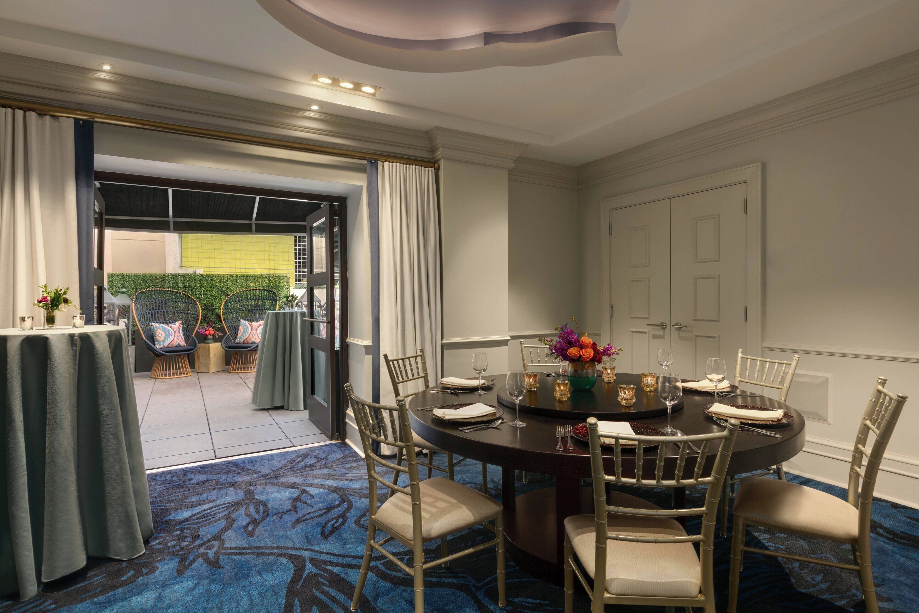 A dining area with a round table, chairs, and a carpeted floor.
