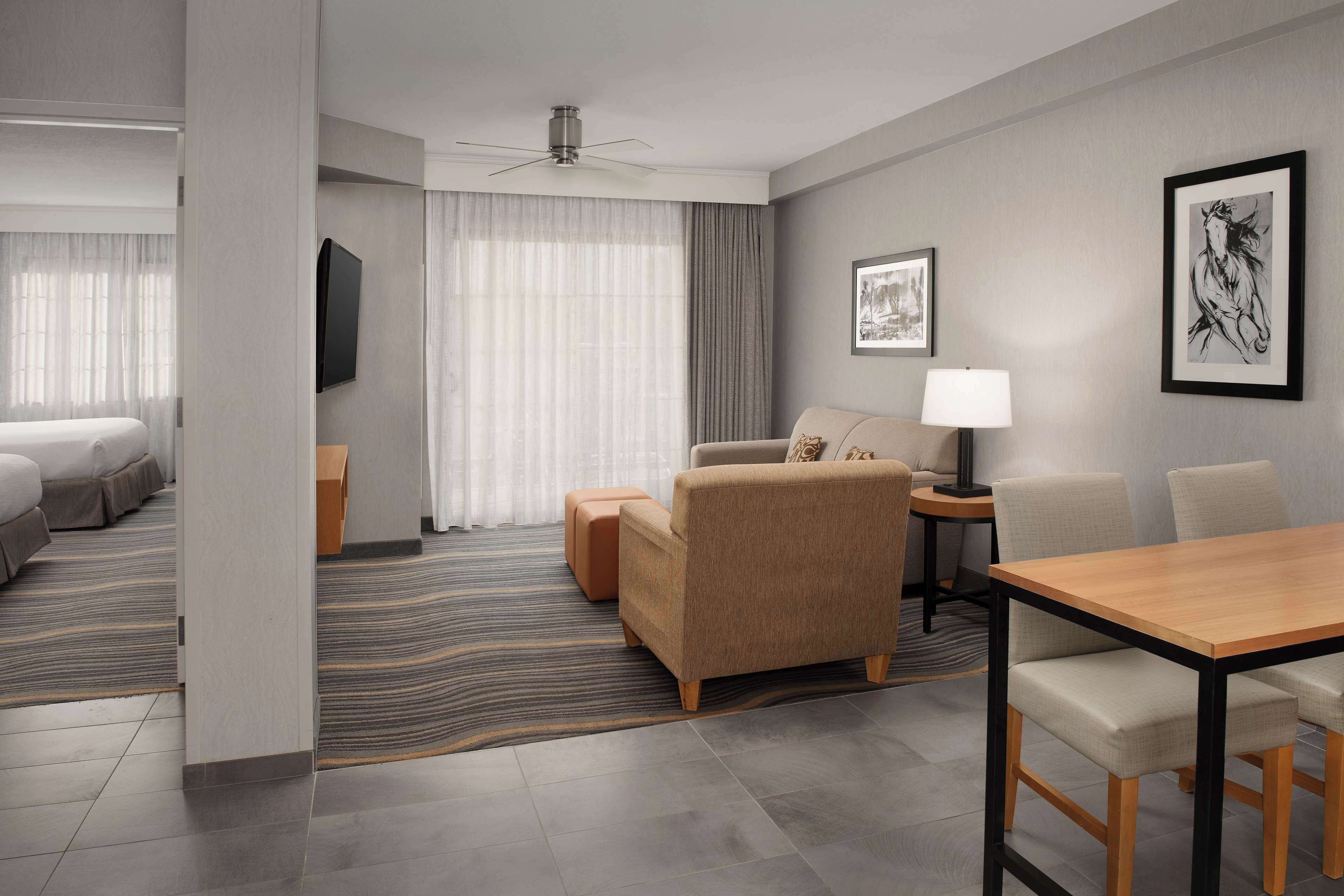 A modern hotel room with a bed, a sofa, a table, and a TV.
