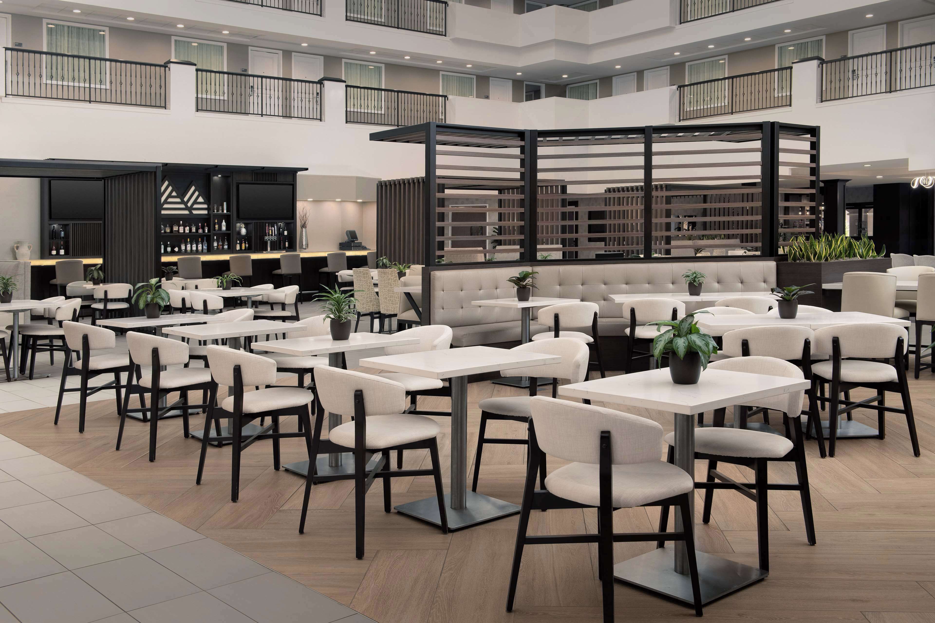 Ein großzügiger Innenbereich mit verschiedenen Sitzgelegenheiten, darunter Tische und Stühle, sowie eine zentrale Lounge mit Sofas.