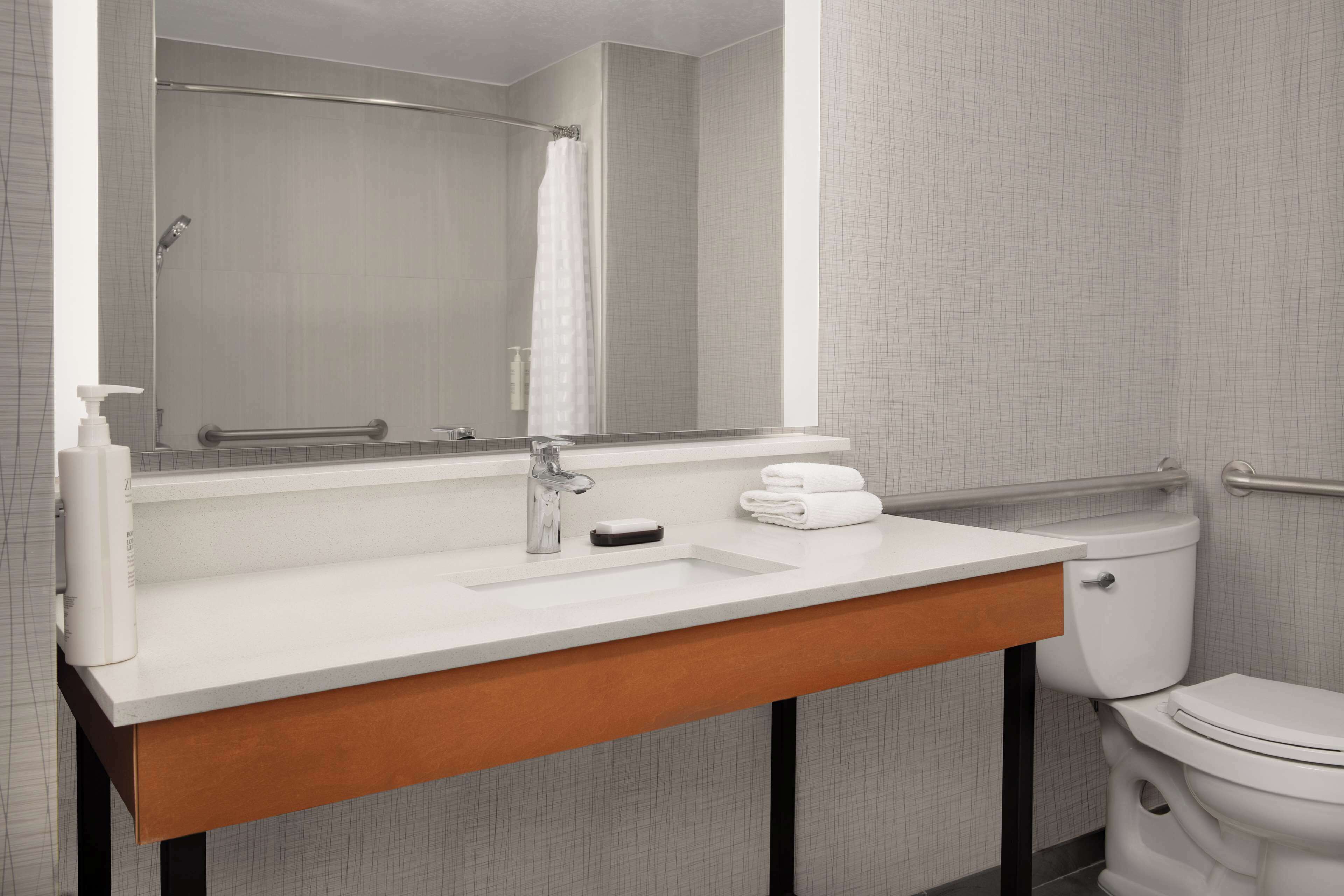Un baño con un lavabo blanco, un espejo, un perchero para toallas y un inodoro.