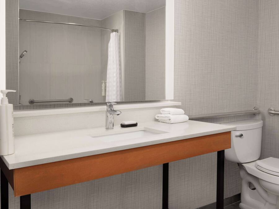 Un baño con un lavabo blanco, un espejo, un perchero para toallas y un inodoro.