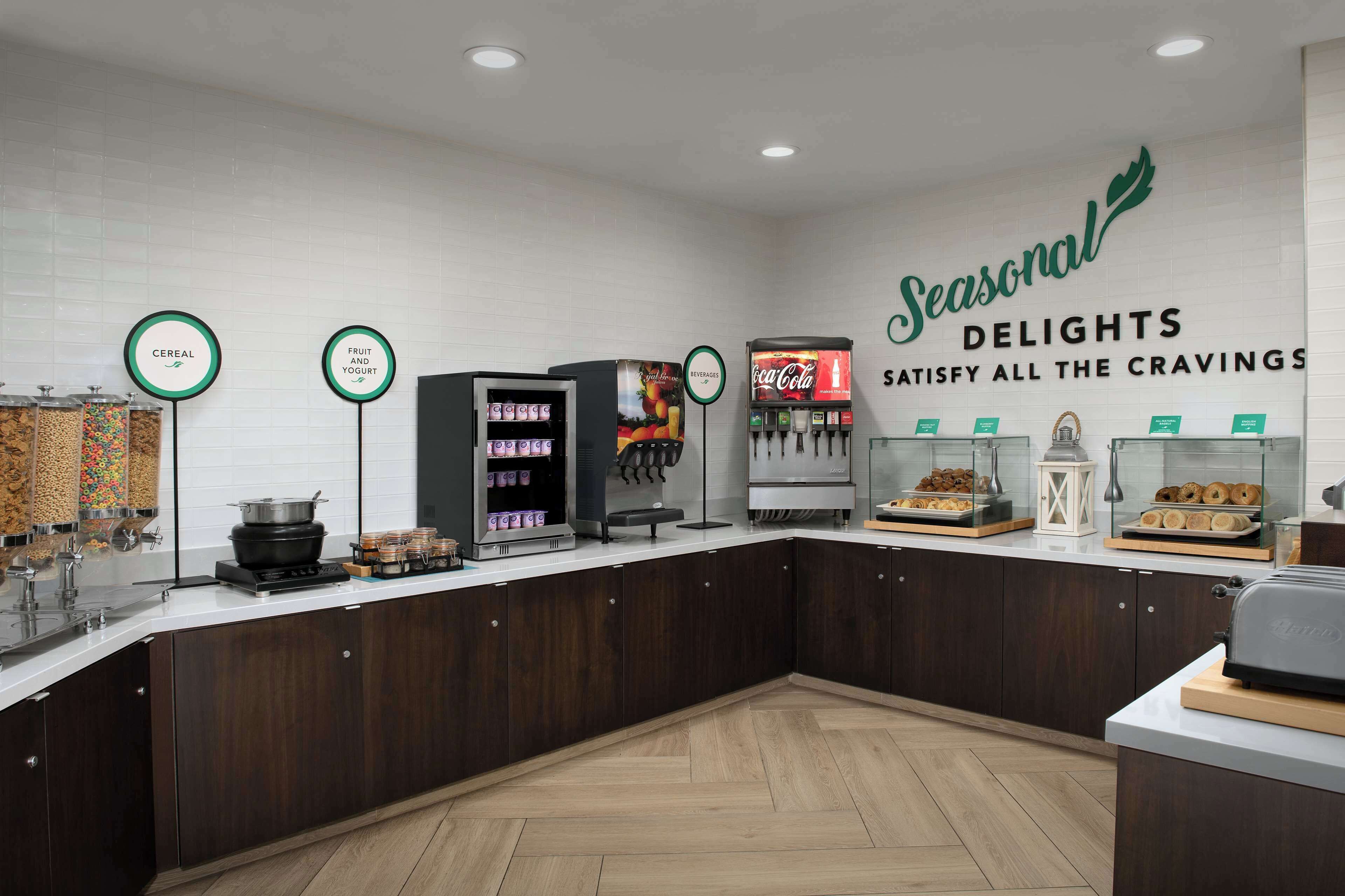 A breakfast bar with cereal, fruit and yogurt, a beverage station, and a display of pastries.