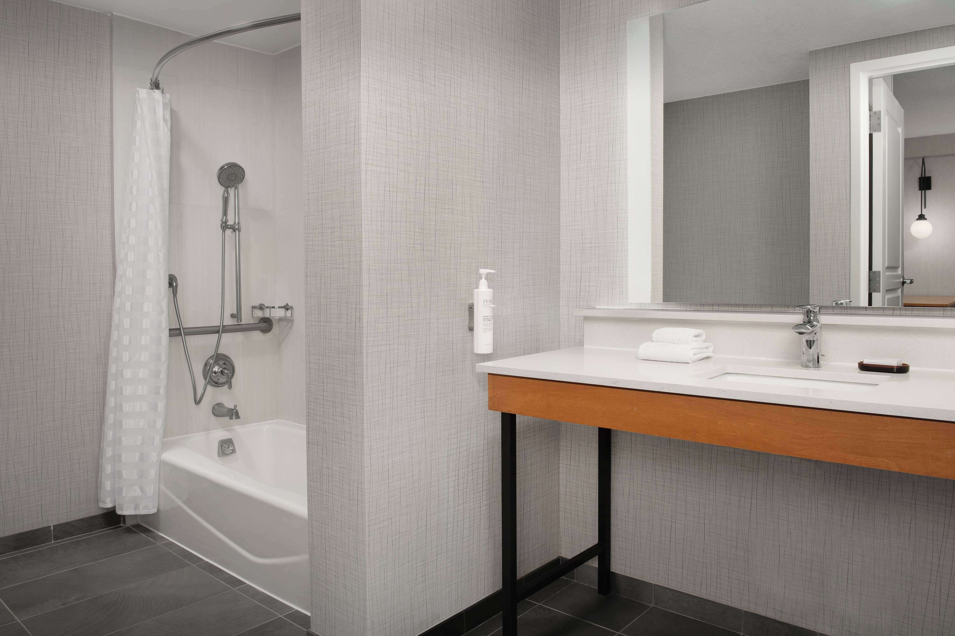 A modern bathroom with a bathtub, shower, and vanity.