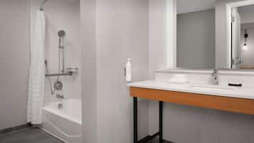 A modern bathroom with a bathtub, shower, and vanity.