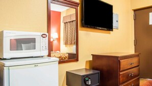 Ein Hotelzimmer mit Mikrowelle, einem kleinen Safe, einem Holzschrank und einem flachbildfernseher, der an der Wand befestigt ist.