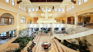 Eine geräumige Lobby mit hoher Decke, mehreren Treppenhäusern und einem zentralen Kronleuchter.