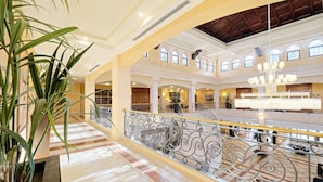 Eine geräumige Lobby mit hohen Decken, Bogenfenstern und einem imposanten Kronleuchter in der Mitte.