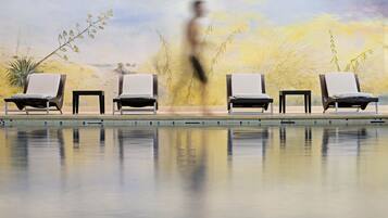 A pool area with lounge chairs and a mural of a desert landscape.