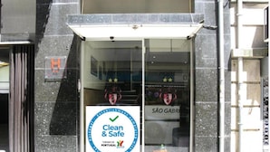 A hotel entrance with a 'Clean & Safe' sign, a 'SÃO GABRIEL' sign, and a 'TURISMO DE PORTUGAL' logo. - Hotel Solar São Gabriel (Porto)