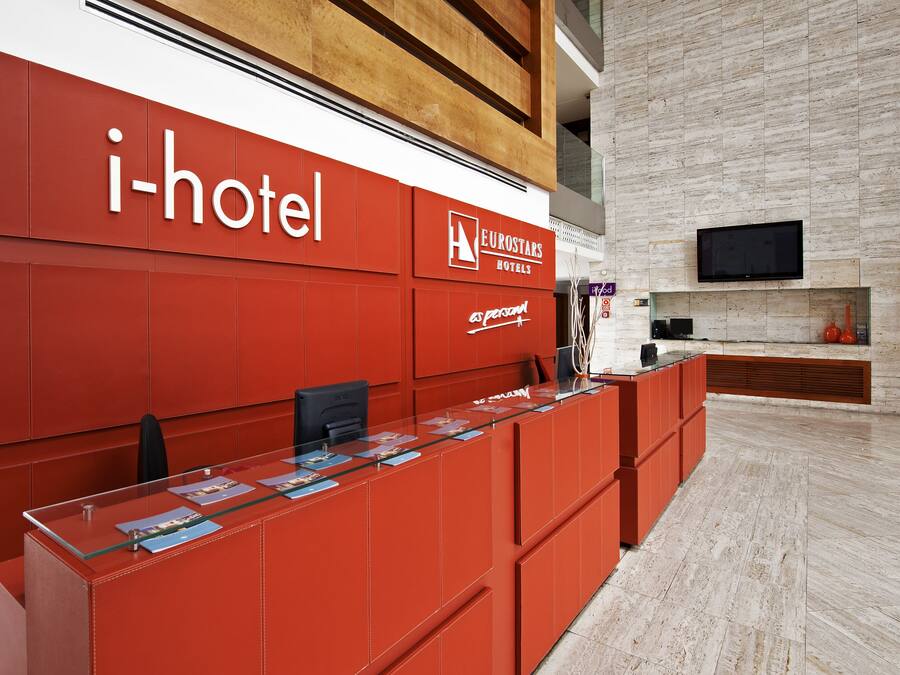 Una recepción con una decoración en tonos rojos y el logotipo de 'i-hotel'.