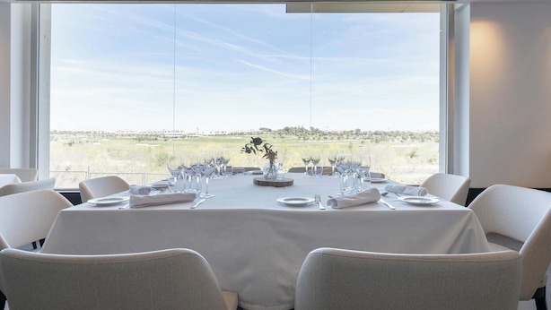 A dining table set for six with a view of a landscape through large windows. - Eurostars i-Hotel (Pozuelo de Alarcon)