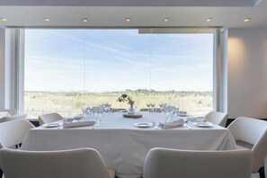 A dining table set for six with a view of a landscape through large windows. - Eurostars i-Hotel (Pozuelo de Alarcon)