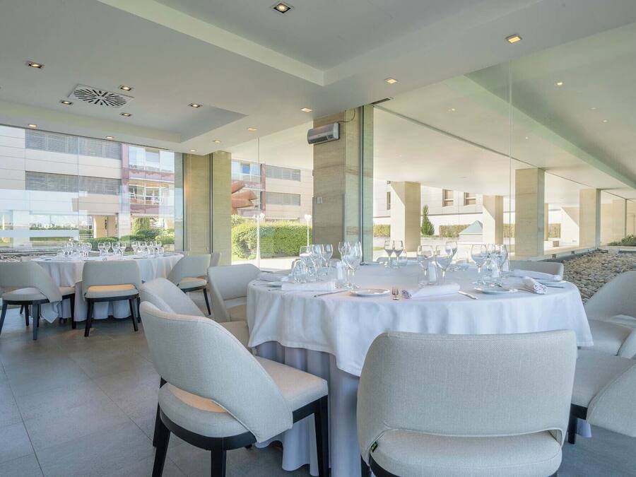 Een moderne eetruimte met gedekte tafels, grote ramen en uitzicht op het exterieur van het gebouw.