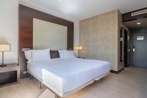A modern hotel room with a large bed, bedside lamps, a wooden headboard, and a built-in wardrobe. - Eurostars i-Hotel (Pozuelo de Alarcon)