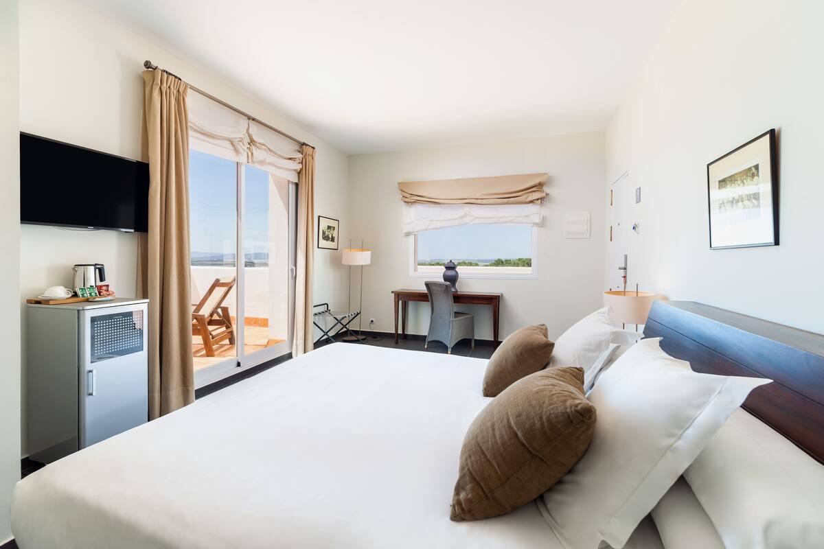 Ein Hotelzimmer mit Bett, Schreibtisch, Stuhl, Fernseher und einem Fenster mit Blick.