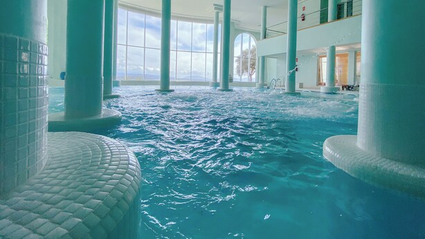 An indoor swimming pool with clear water, surrounded by large columns and a high ceiling. - Hotel Fairplay Golf & Spa Resort-by Grupo Tribu (Benalup-Casas Vieja)