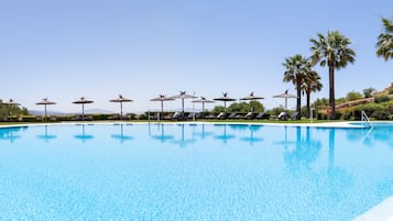Una piscina al aire libre de temporada, sombrillas, tumbonas