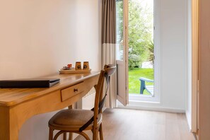 Een houten bureau met een stoel, een laptop en twee flessen erop.