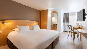 A hotel room with a large bed, wooden headboard, bedside lamps, a desk with a chair, a television, and a mirror. - Sure Hotel by Best Western Plaisir (Plaisir)
