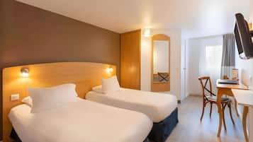 Ein Hotelzimmer mit zwei Betten, einem Schreibtisch, einem Stuhl, einem Spiegel und einem Kleiderschrank.
