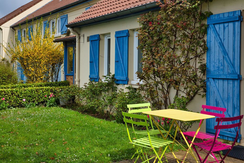 A house with a garden, a table, and two chairs.