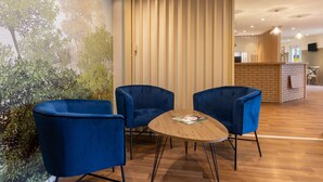 A room with three blue chairs around a wooden table, a brick wall, and a mural of trees. - Sure Hotel by Best Western Plaisir (Plaisir)