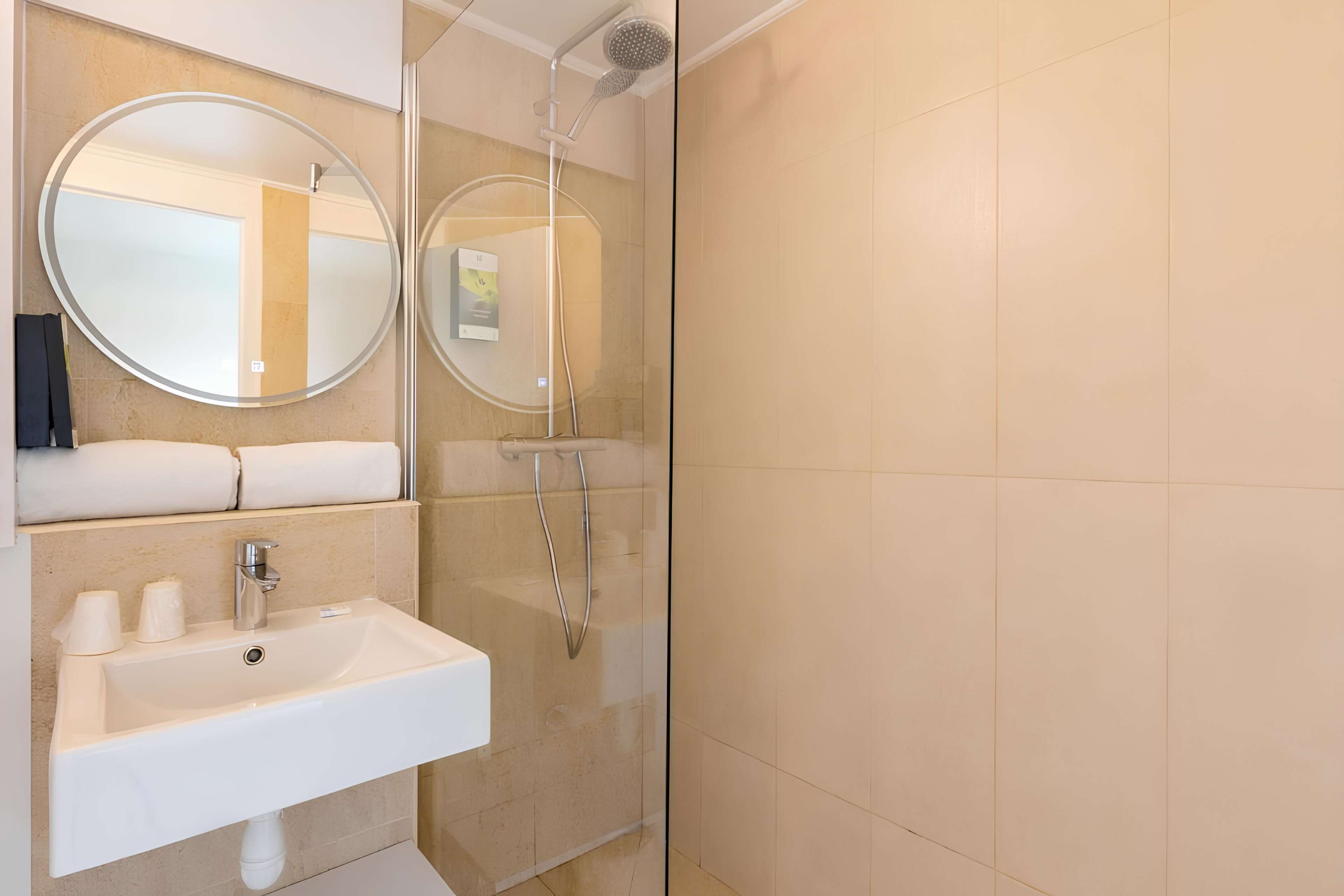 A modern bathroom with a sink, two mirrors, and a shower.