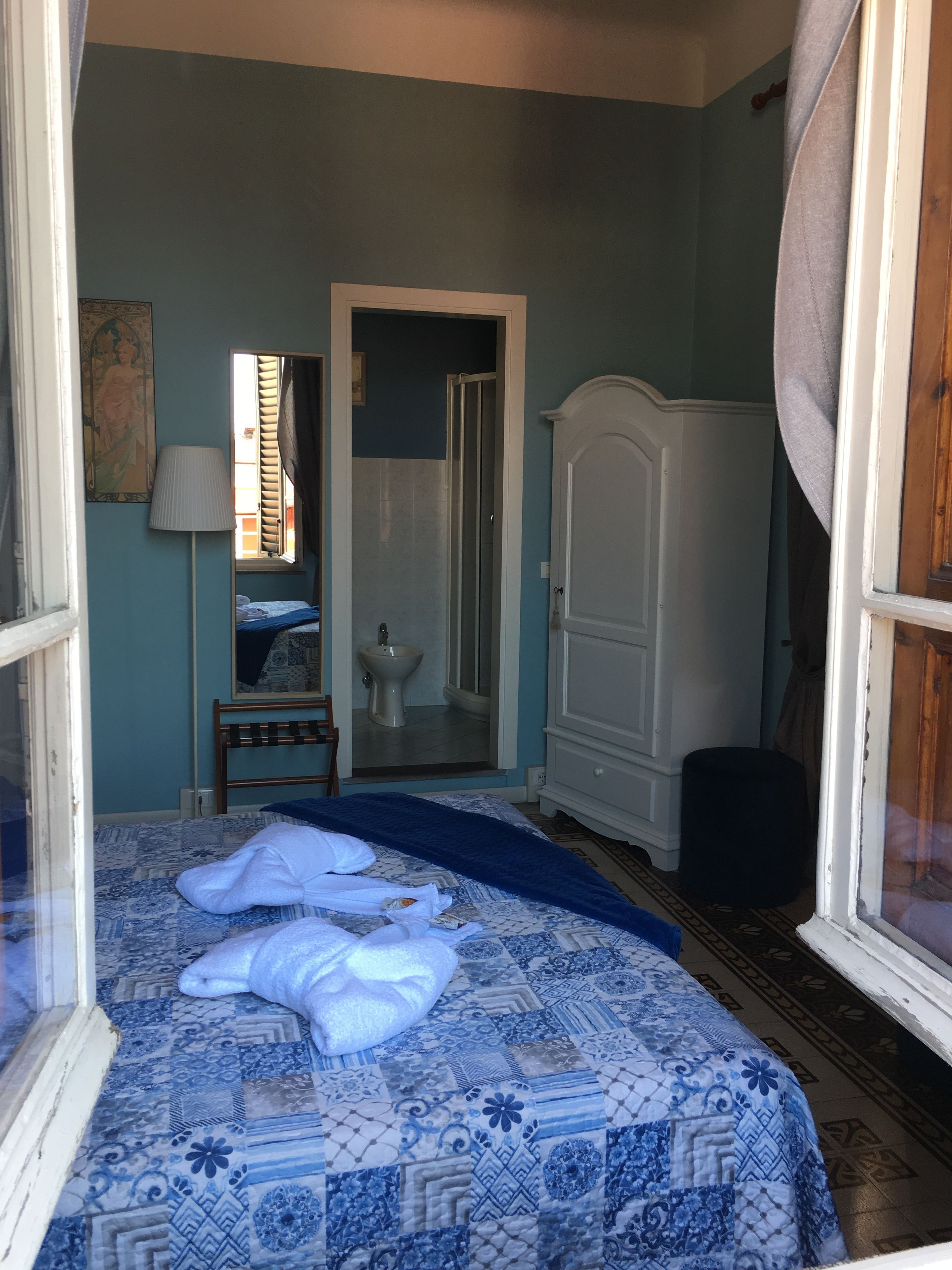 A bedroom with a bed, a wardrobe, a mirror, and a window.