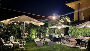 An outdoor patio area with multiple seating arrangements, including chairs and tables, under large umbrellas. - Lucca in Villa San Donato (Lucca)