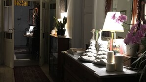 A dimly lit hallway with a chandelier, a wooden dresser with a mirror, and a potted plant. - Lucca in Villa San Donato (Lucca)